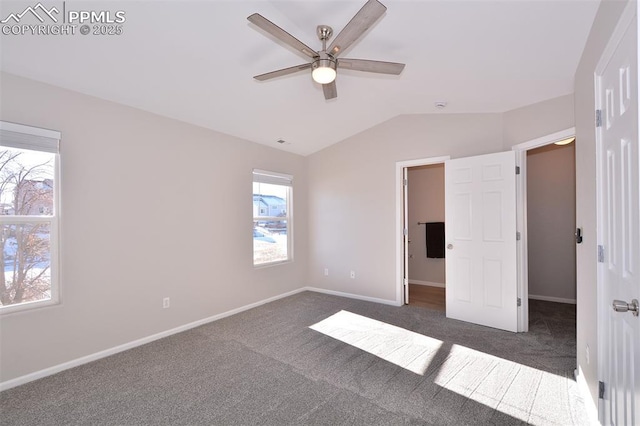 unfurnished bedroom featuring ceiling fan, a walk in closet, lofted ceiling, and dark colored carpet