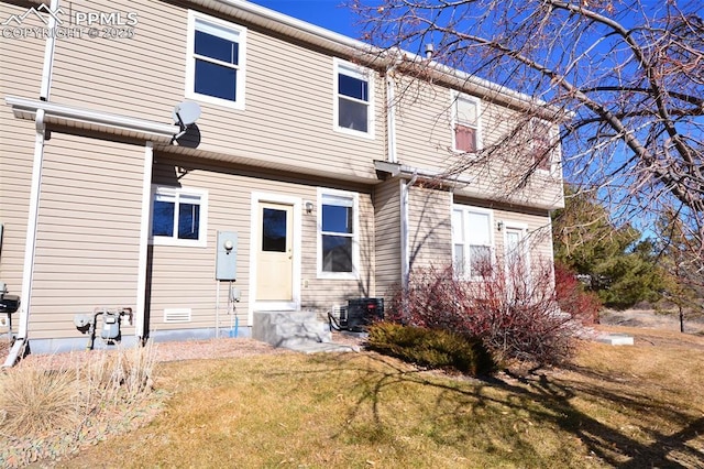 rear view of house with a lawn and cooling unit