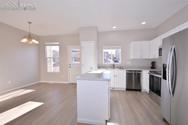 kitchen with pendant lighting, white cabinets, stainless steel appliances, and a chandelier