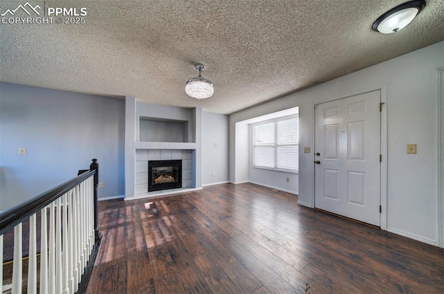 unfurnished living room with built in features, a tiled fireplace, dark hardwood / wood-style flooring, and a textured ceiling