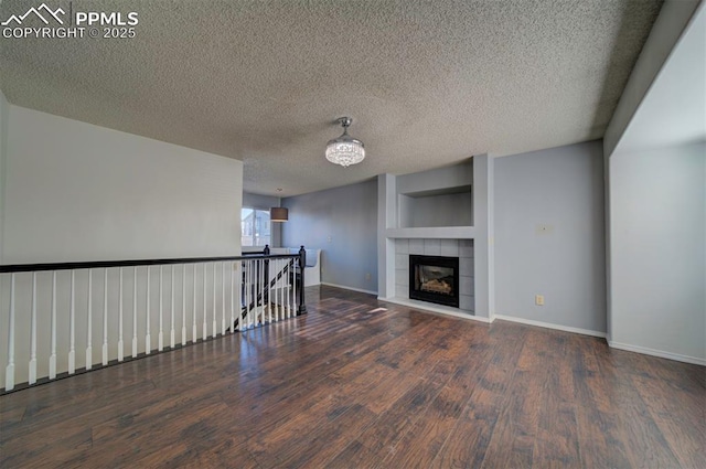 unfurnished living room with a textured ceiling, dark hardwood / wood-style floors, a notable chandelier, and a fireplace