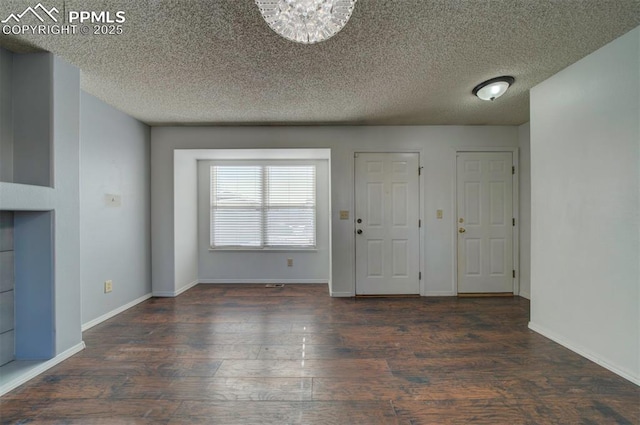 entrance foyer with a textured ceiling, dark hardwood / wood-style floors, and a chandelier