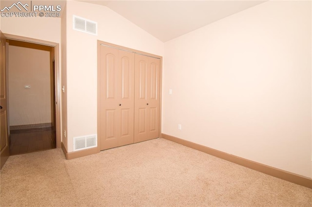 unfurnished bedroom with a closet, carpet flooring, and lofted ceiling