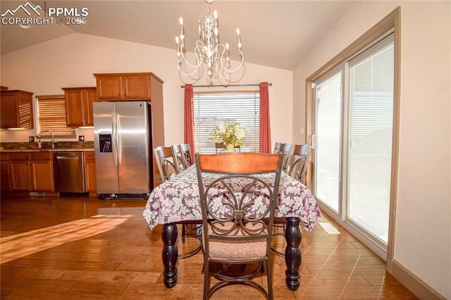 dining room featuring sink, vaulted ceiling, a chandelier, and dark wood-type flooring