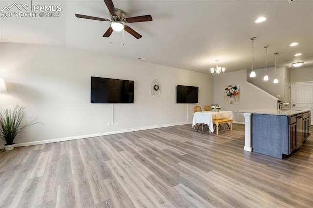 unfurnished living room with ceiling fan with notable chandelier, hardwood / wood-style flooring, and sink