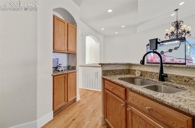 kitchen featuring sink, light hardwood / wood-style floors, decorative light fixtures, and light stone counters