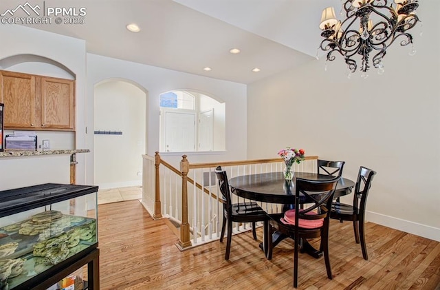 dining area with light wood-type flooring and an inviting chandelier