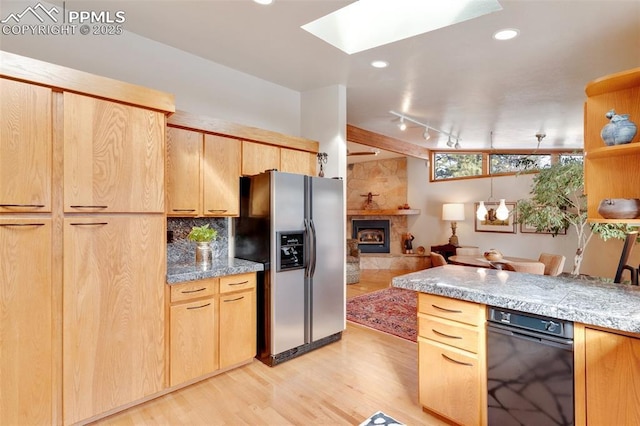 kitchen featuring light hardwood / wood-style flooring, a skylight, a fireplace, light brown cabinetry, and stainless steel fridge with ice dispenser