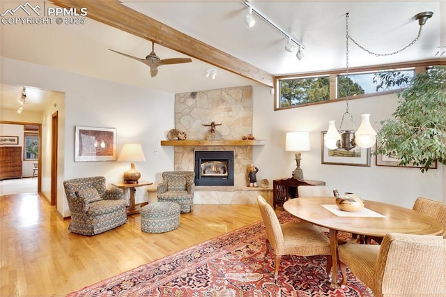 dining space featuring hardwood / wood-style flooring, ceiling fan, a fireplace, and beamed ceiling