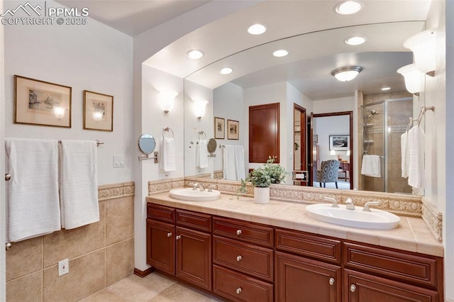 bathroom featuring walk in shower, vanity, tile patterned flooring, and tile walls