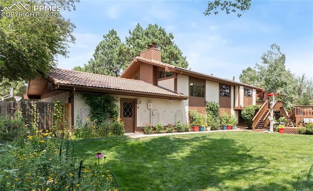 back of property featuring a wooden deck and a yard