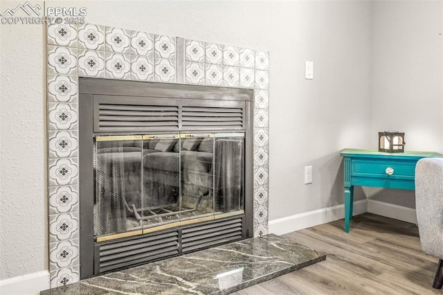 interior details featuring a tile fireplace and hardwood / wood-style flooring