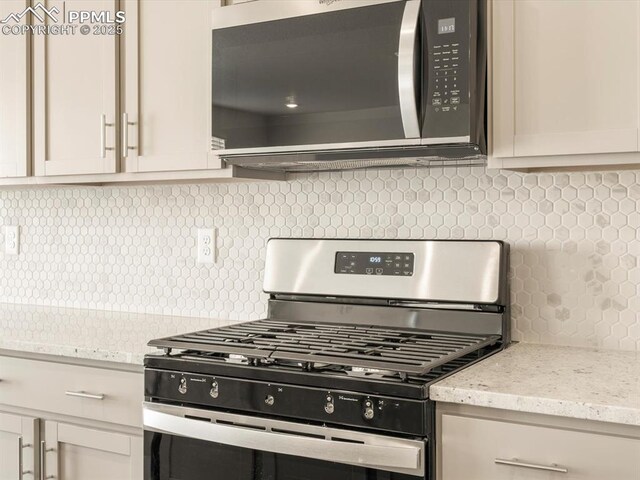 kitchen with stainless steel gas stove, light stone countertops, white cabinets, and decorative backsplash