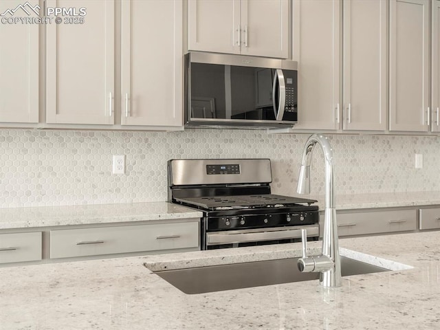 kitchen featuring white cabinetry, stainless steel appliances, light stone counters, and tasteful backsplash