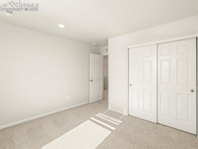 unfurnished bedroom featuring a closet and light colored carpet