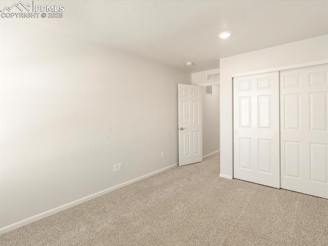 unfurnished bedroom featuring light colored carpet and a closet