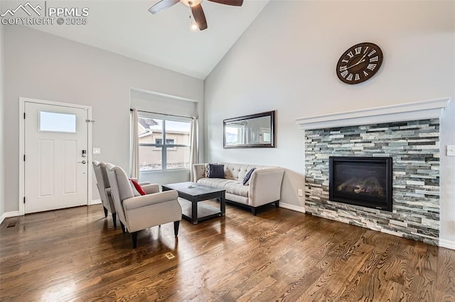 living room featuring ceiling fan, high vaulted ceiling, dark wood-type flooring, and a stone fireplace