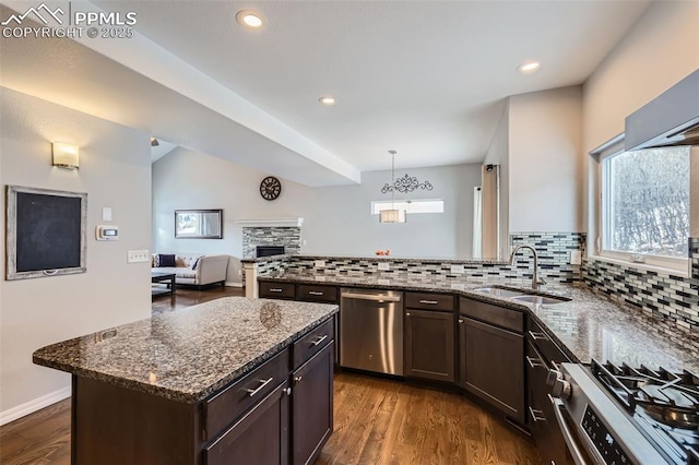 kitchen featuring hanging light fixtures, sink, light stone counters, decorative backsplash, and stainless steel appliances