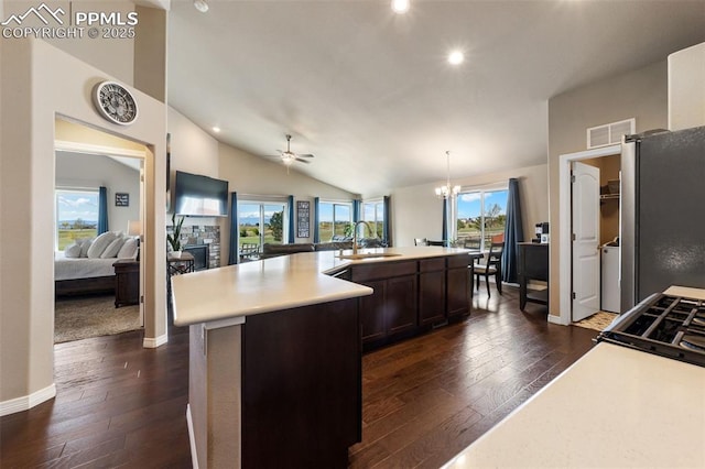 kitchen featuring vaulted ceiling, pendant lighting, a center island with sink, sink, and stainless steel fridge