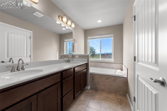 bathroom with tiled bath, tile patterned floors, and vanity