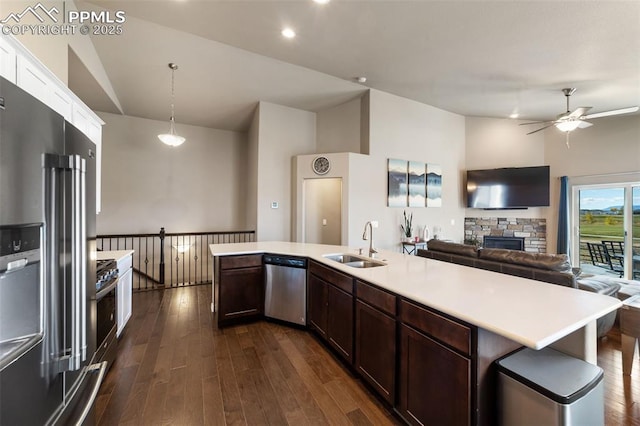 kitchen with a fireplace, pendant lighting, sink, stainless steel appliances, and dark brown cabinets