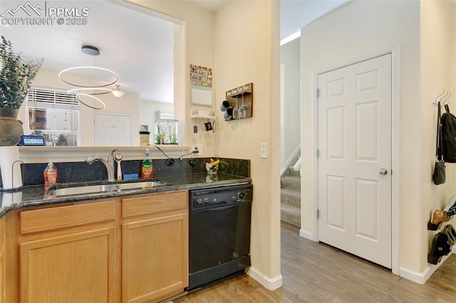 kitchen featuring dark stone counters, dishwasher, sink, and light hardwood / wood-style flooring