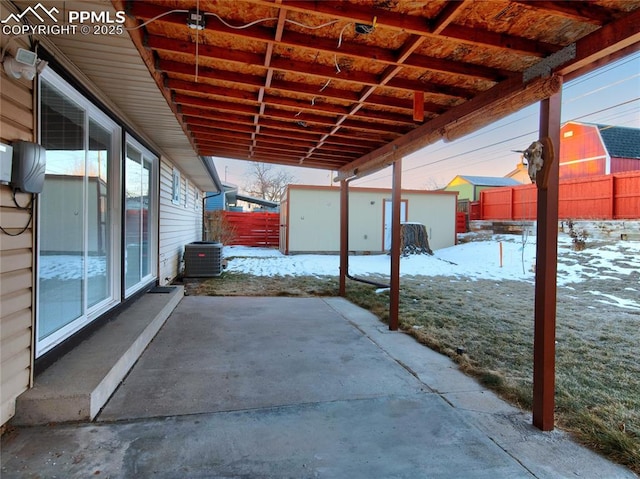 snow covered patio featuring a storage shed and cooling unit