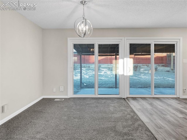 spare room with a textured ceiling, a chandelier, and hardwood / wood-style floors