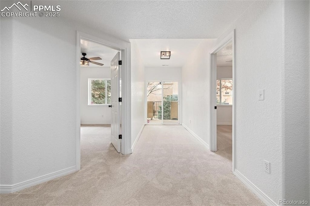 hallway with a textured ceiling and light colored carpet