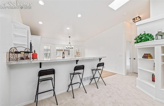 kitchen with white cabinetry, a kitchen bar, kitchen peninsula, a notable chandelier, and decorative light fixtures