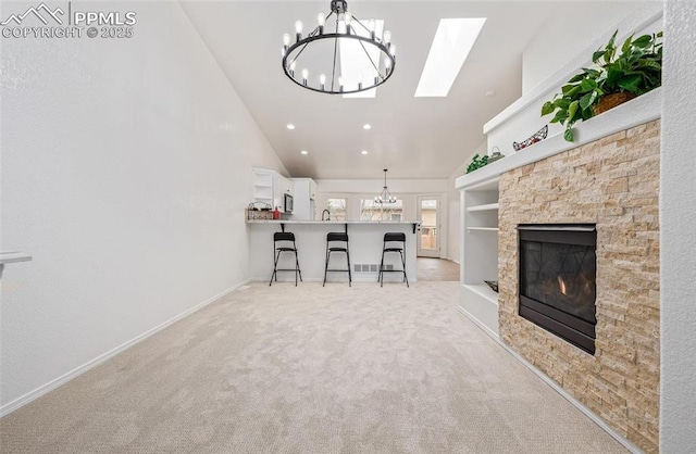 unfurnished living room with light carpet, built in features, a stone fireplace, and high vaulted ceiling