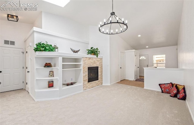 carpeted living room featuring a tile fireplace, a chandelier, and vaulted ceiling