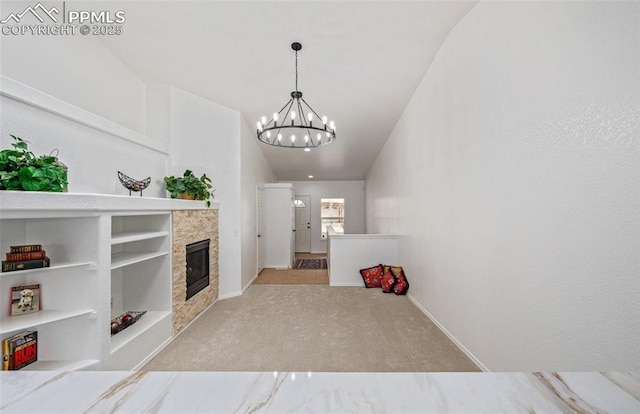 unfurnished living room featuring a fireplace, an inviting chandelier, light colored carpet, and built in shelves