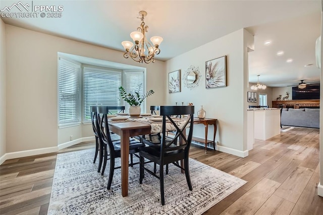 dining area with ceiling fan with notable chandelier and light hardwood / wood-style flooring