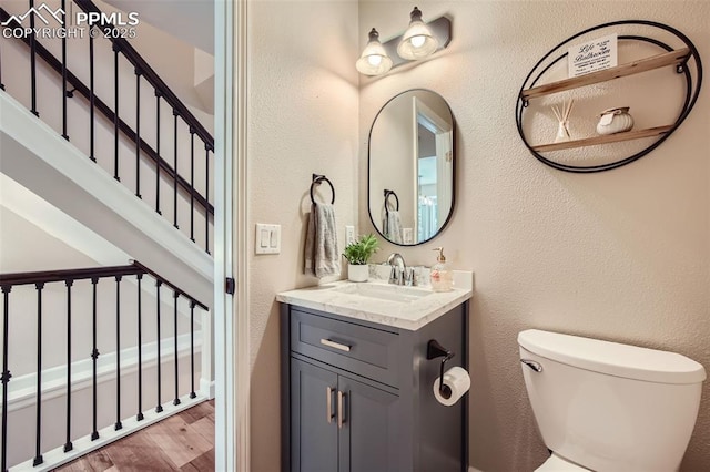 bathroom with toilet, vanity, and hardwood / wood-style flooring