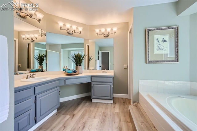 bathroom featuring a relaxing tiled tub, wood-type flooring, and vanity