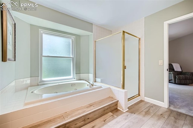 bathroom featuring plus walk in shower, a healthy amount of sunlight, and hardwood / wood-style floors