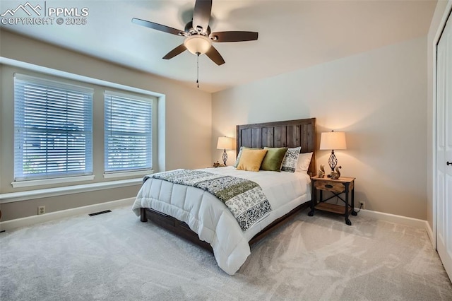 bedroom with light carpet, ceiling fan, a closet, and multiple windows