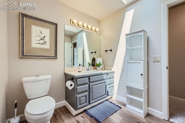 bathroom with toilet, vanity, a skylight, and hardwood / wood-style floors