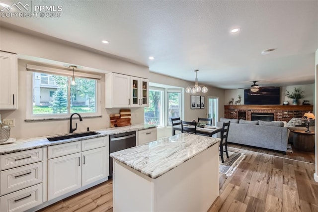 kitchen featuring light stone countertops, white cabinets, a brick fireplace, and sink