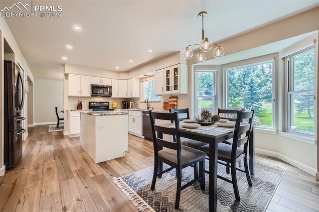 dining space featuring an inviting chandelier, light hardwood / wood-style flooring, and sink