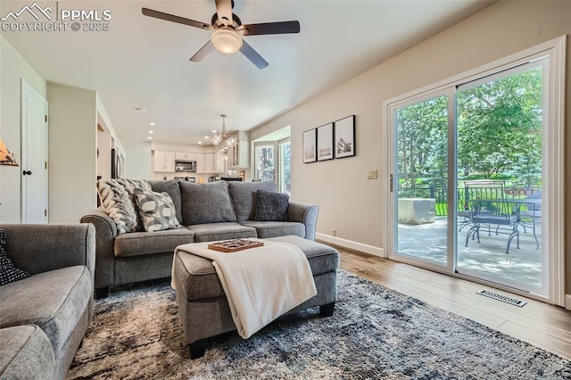 living room with ceiling fan with notable chandelier and hardwood / wood-style flooring