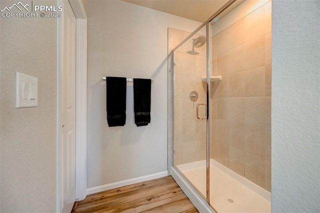 bathroom with wood-type flooring and a shower with shower door