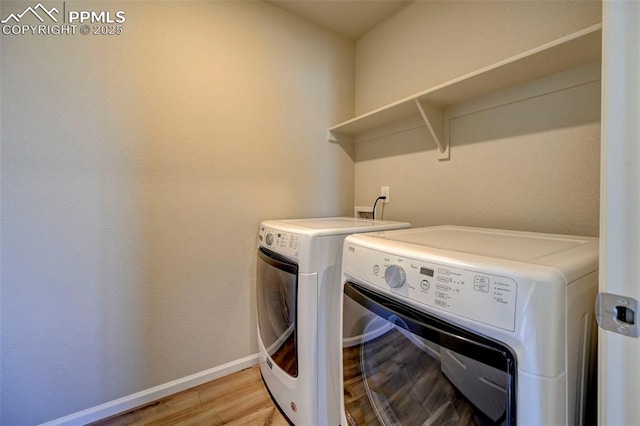 laundry area with washer and clothes dryer and light hardwood / wood-style flooring