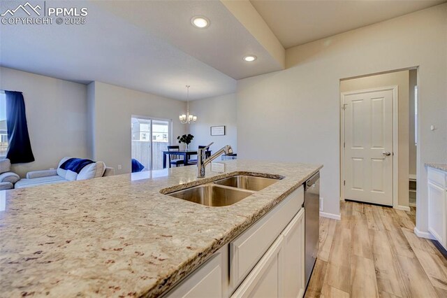 kitchen with sink, light stone counters, decorative light fixtures, dishwasher, and white cabinets