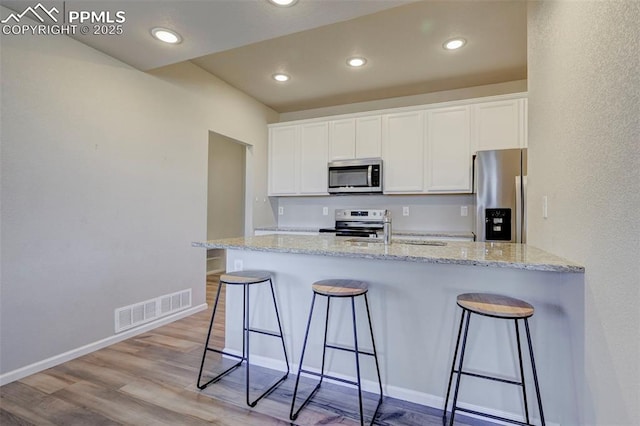 kitchen with appliances with stainless steel finishes, a breakfast bar, and white cabinets