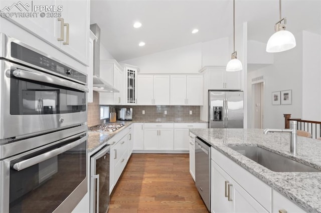 kitchen with lofted ceiling, decorative backsplash, sink, white cabinetry, and stainless steel appliances