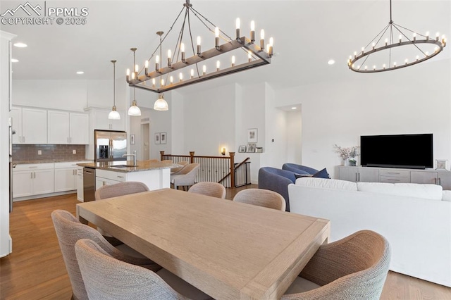 dining area featuring light hardwood / wood-style floors and high vaulted ceiling