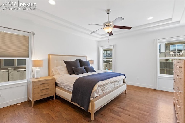 bedroom featuring ceiling fan, a tray ceiling, and dark hardwood / wood-style flooring