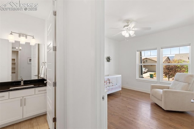 bedroom with ceiling fan, sink, a crib, and light hardwood / wood-style flooring